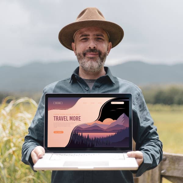 Portrait of Spire Forge founder with laptop displaying website against mountain backdrop—blending digital design and natural aspiration.