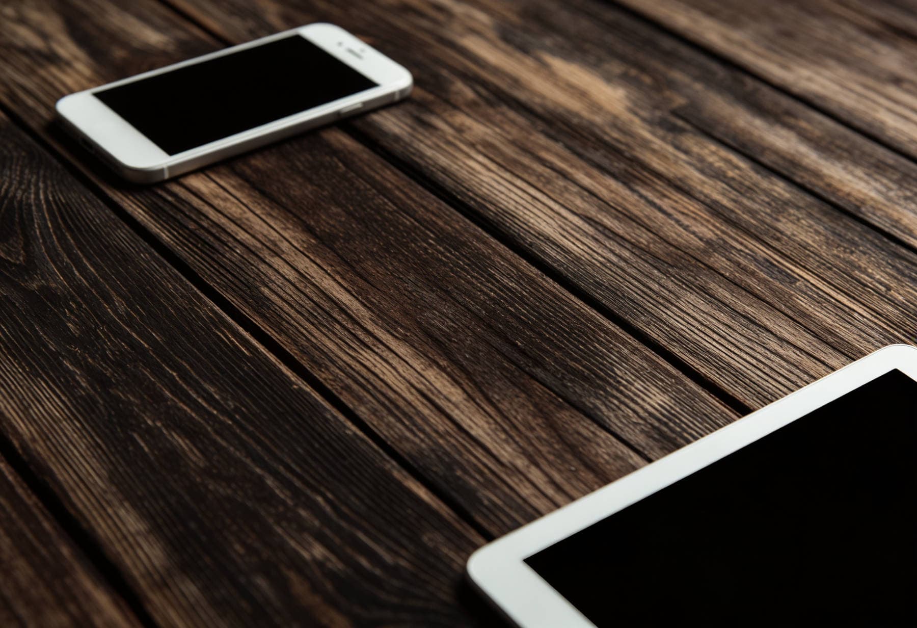Smartphone and tablet on rustic table showcasing Spire Forge web craftsmanship.